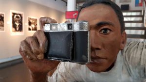 Sculpture of a man holding up his photo camera and looking through the viewfinder.
