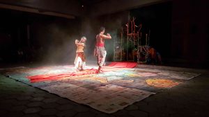 Traditional Javanese dance performance shows one man and one woman posed towards each other.