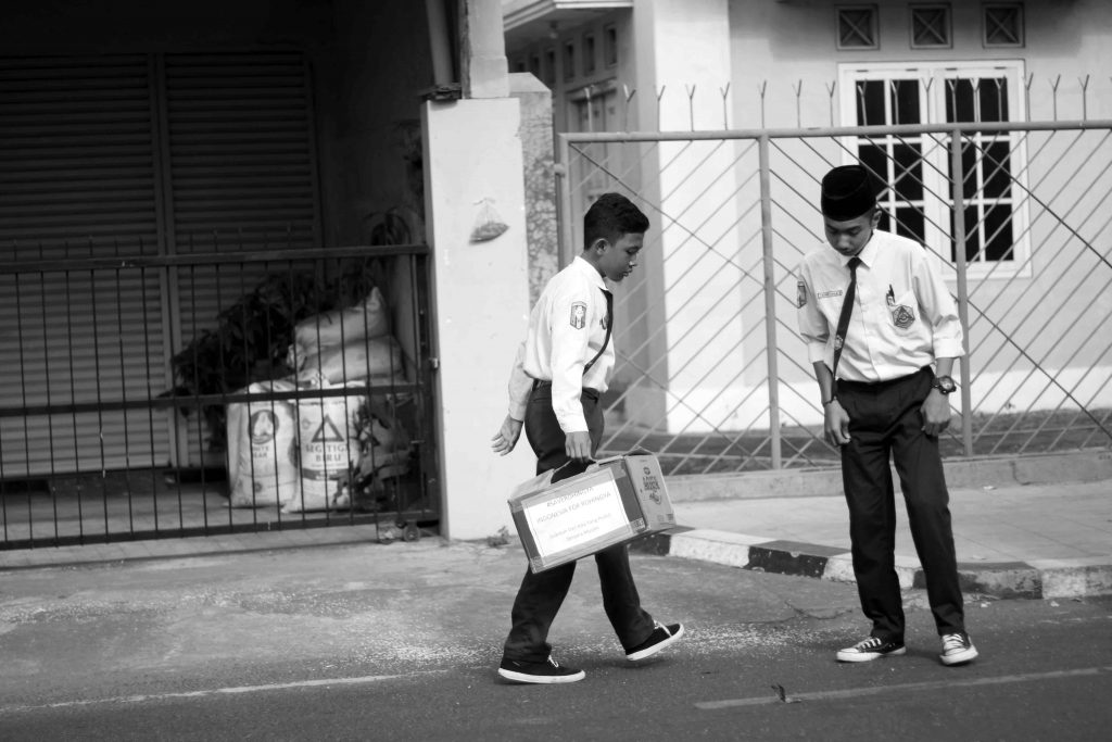 Two boys in school uniform stand in the street.