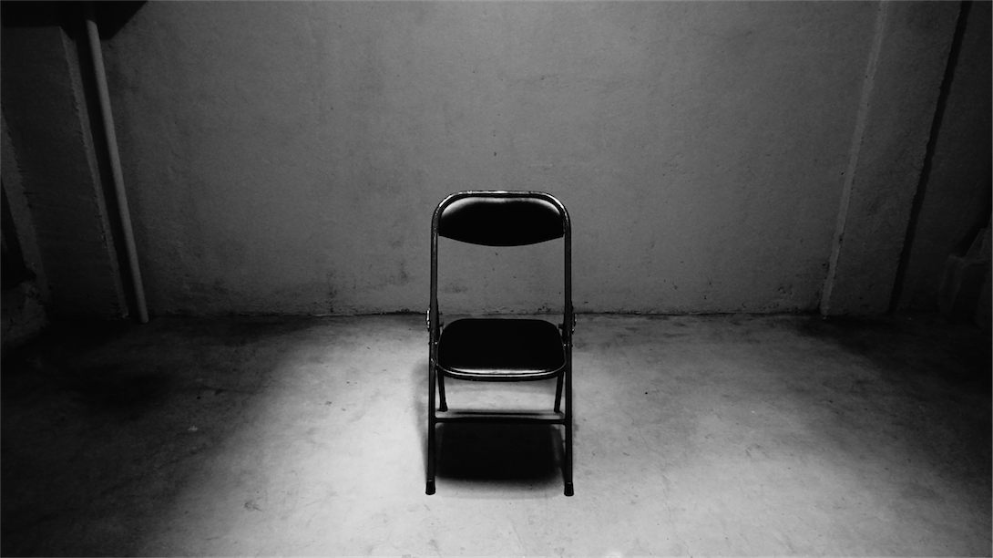 A folding metal chair in an empty space/Kursi logam terlipat di ruang kosong