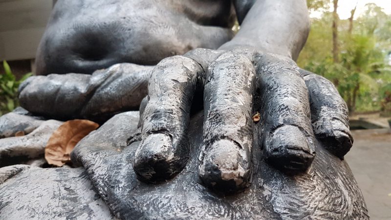 Close up view of a chunky bronze hand, detail of a larger sculpture.
