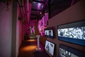 Exhibition view of video installation with multiple screens showing black and white images of young men and women.