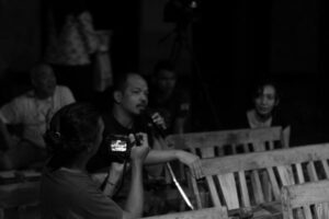 An audience member speaks into a mic while another person videos him.